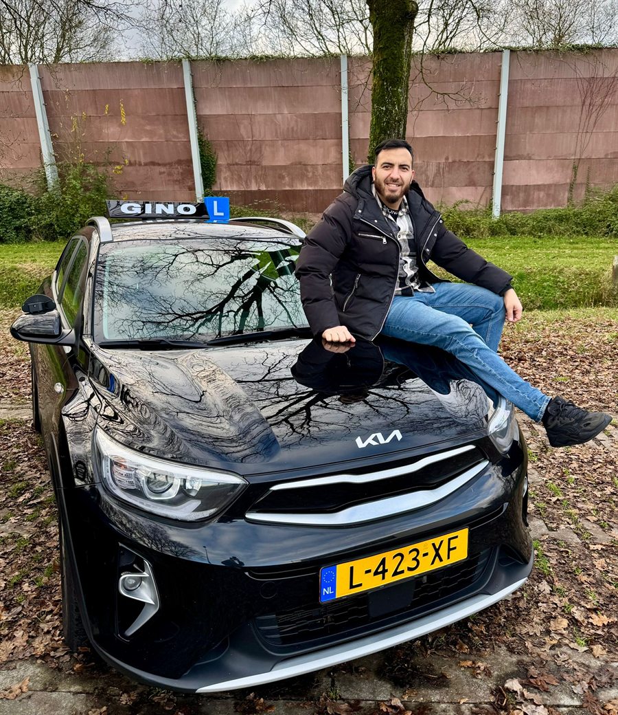 Mehmet op de zwarte Kia-lesauto van Rijschool Gino